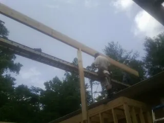 Carpenter setting a ridge beam over a new addition frame — Ice Dam Removal by Roofing Brothers in Olanta