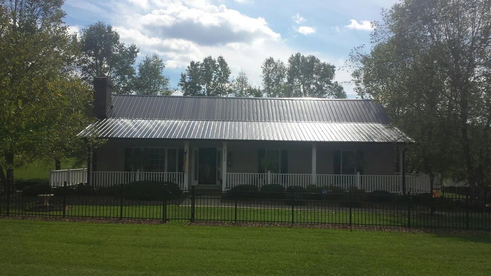 Gray metal roof on a brick ranch with a full width front porch — Gutter Guard Installation work by our crew in Olanta